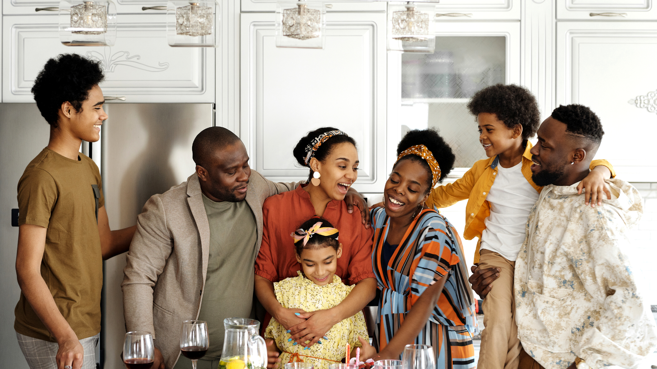 A family stands around the kitchen lovingly.